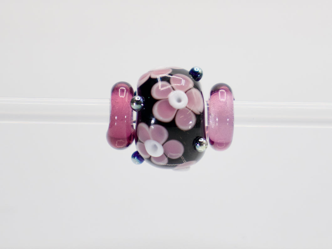 a pink and black bead with flowers on it