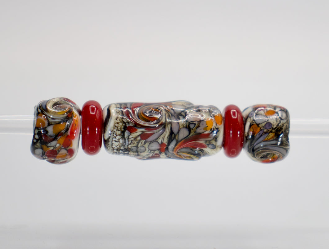 a glass bead with red and white designs on it